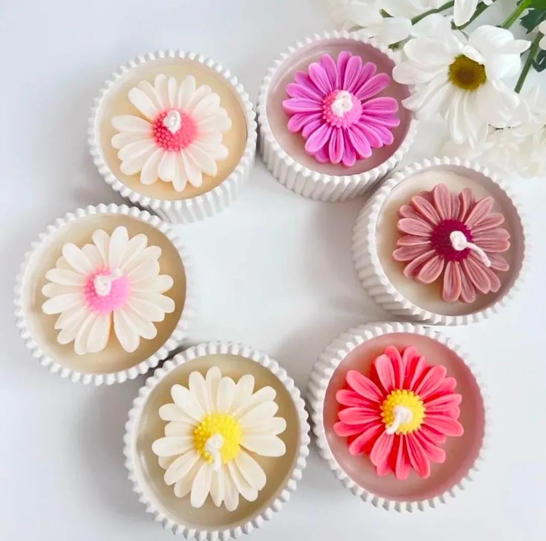 Cupcakes decorated with flower-shaped candles on a white background