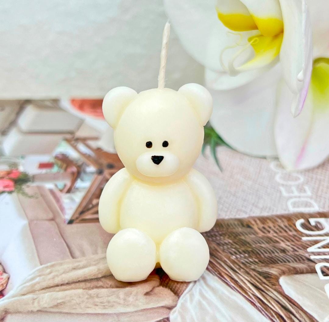 Teddy bear-shaped candle on a surface with a blurred background