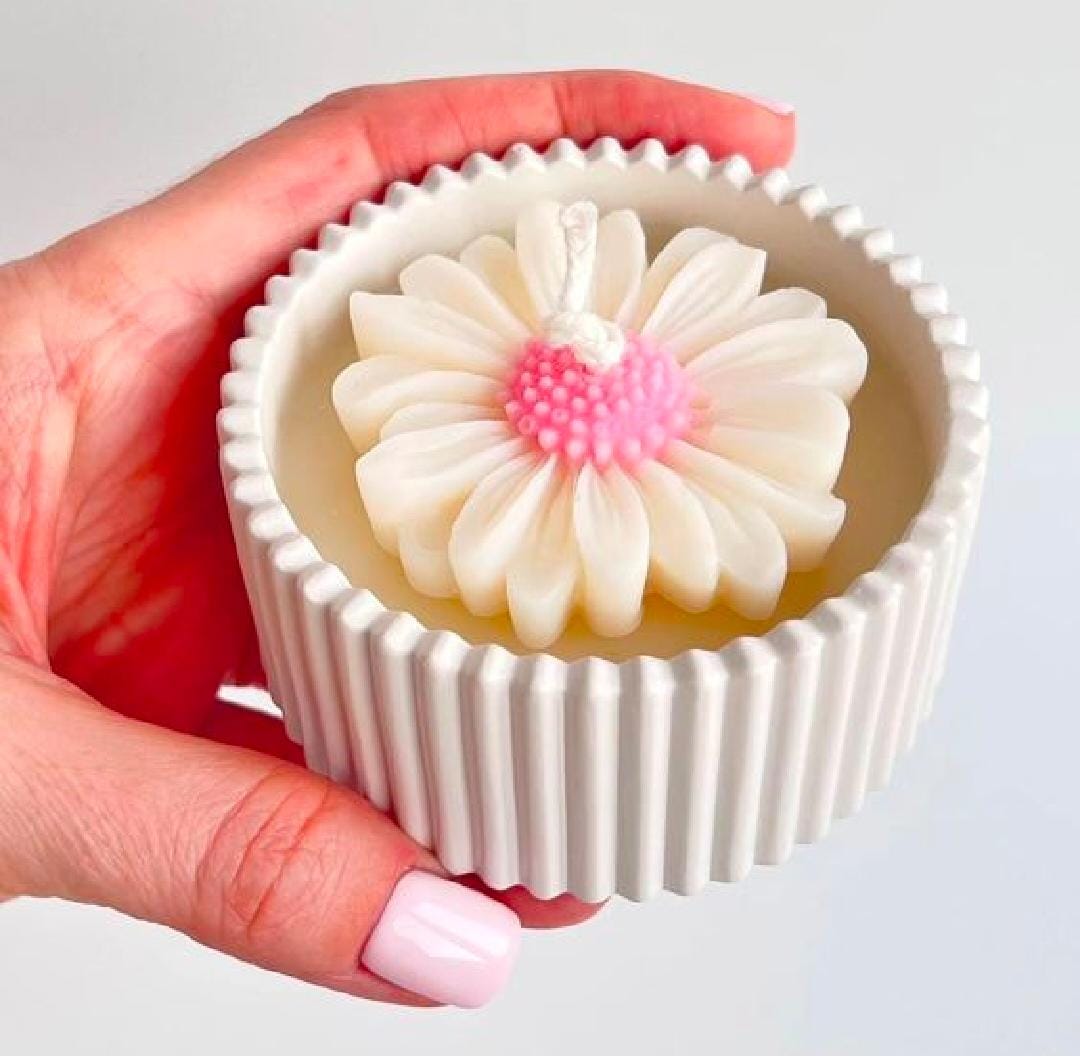 Hand holding a cupcake with white frosting and pink center against a light gray background