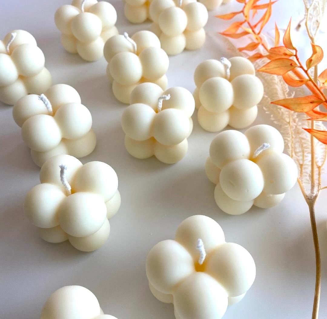 White bubble-shaped candles on a white surface with decorative elements.