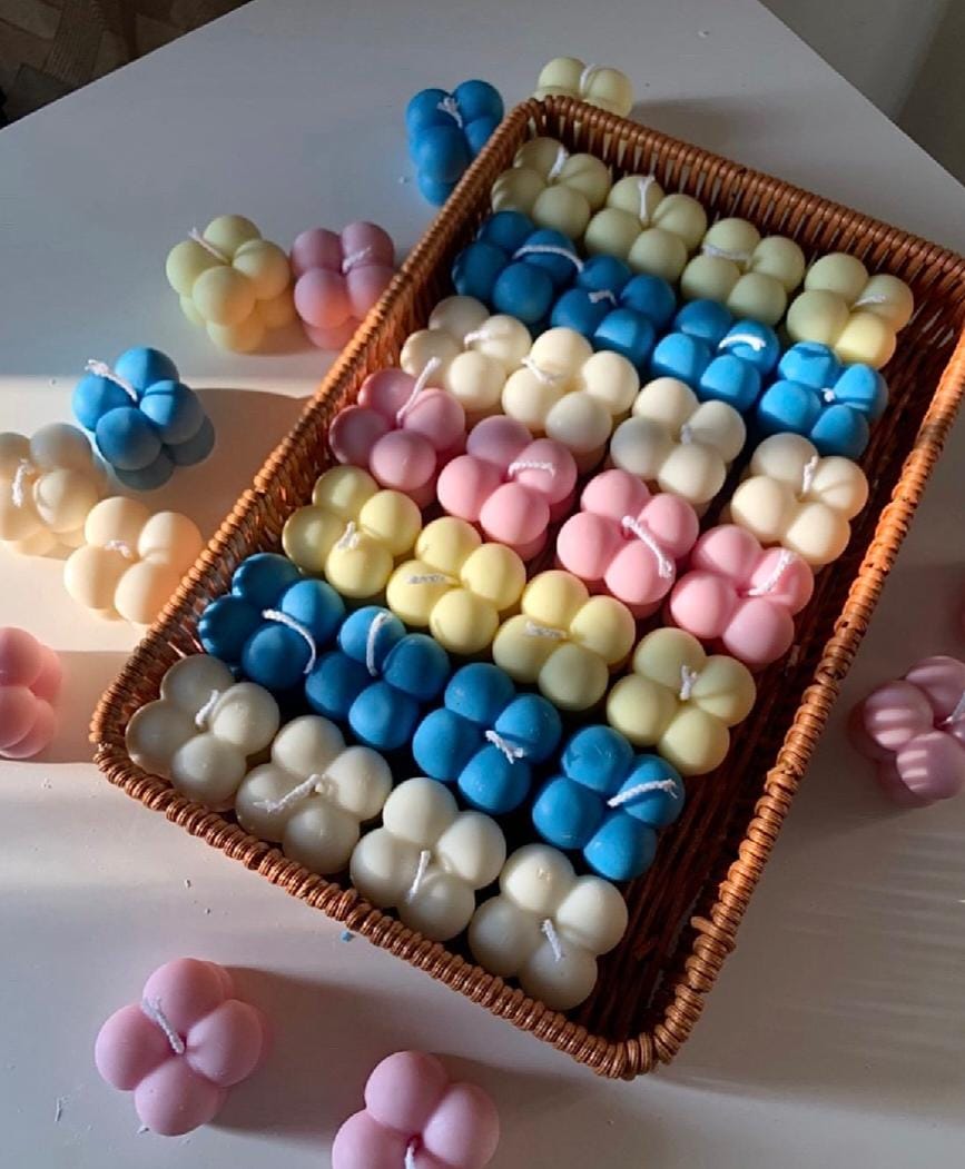 Assorted colorful candles in a wicker basket on a white surface