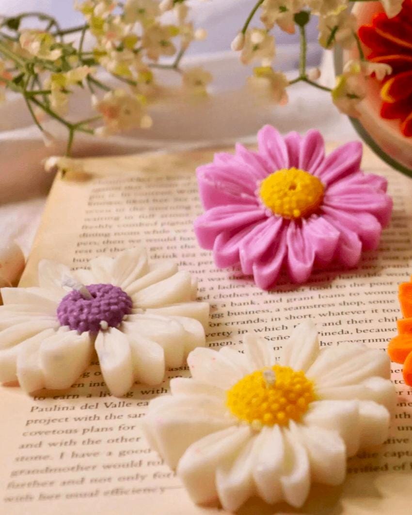 Pink and white ceramic daisy flowers on a book with flowers in the background