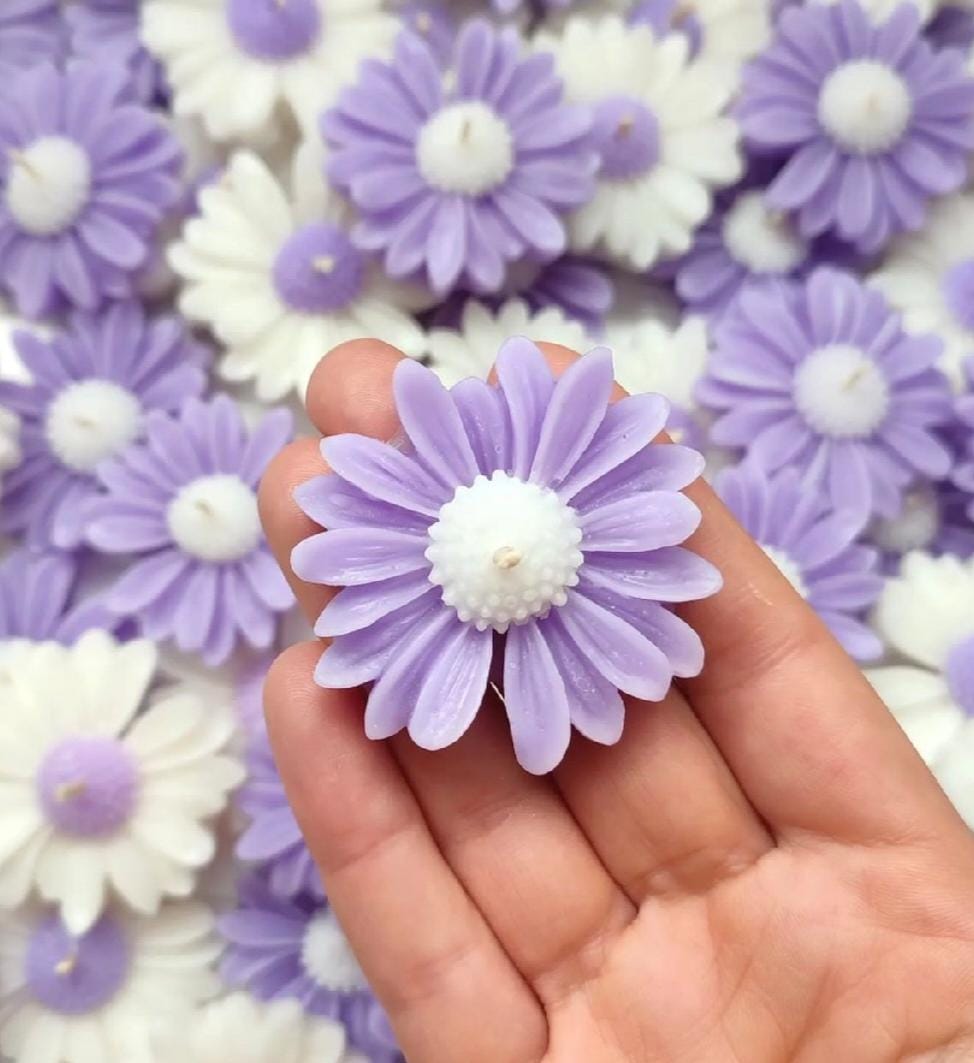 Hand holding a purple flower-shaped candy with more candies in the background