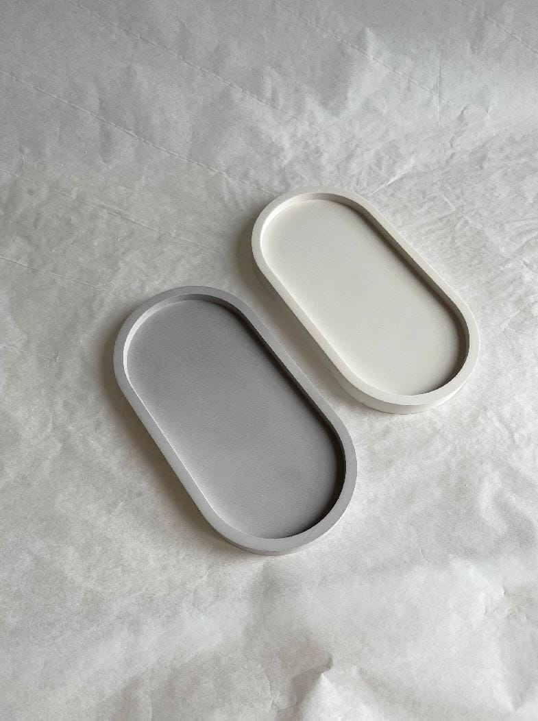 Two oval ceramic trays on a textured gray surface