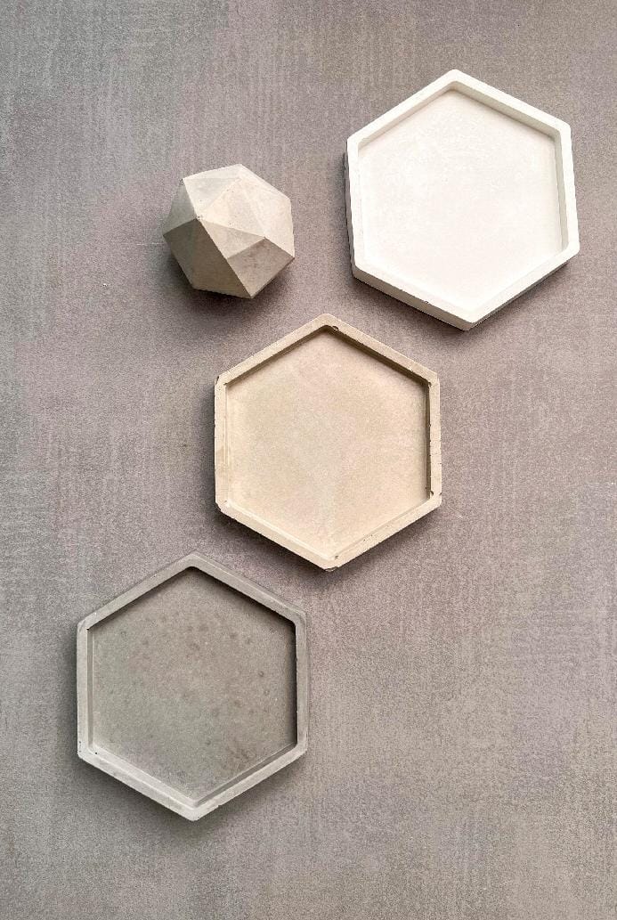Set of four hexagonal concrete wall shelves on a gray textured wall.