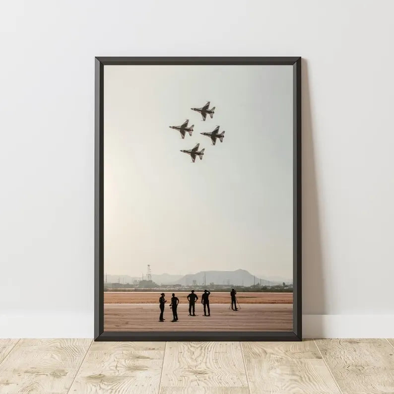 Framed artwork of four airplanes flying over a group of people on a runway.