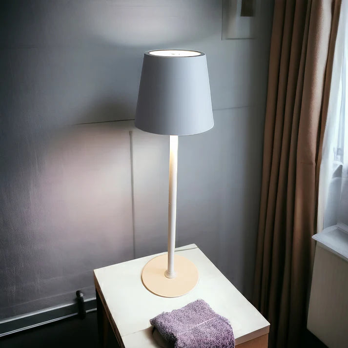 Table lamp with a gray shade on a white table next to a window