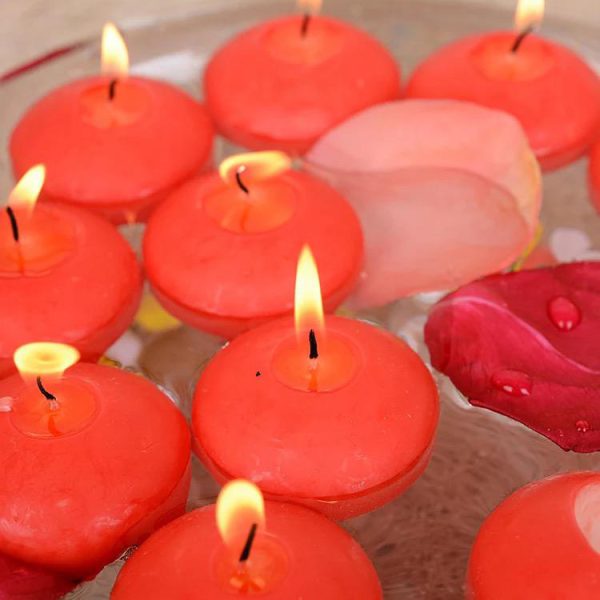 Red floating candles with pink petals on a water surface