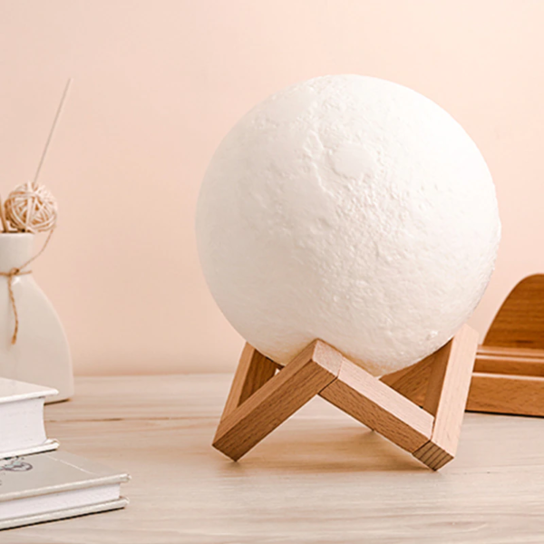 Moon lamp on a wooden stand with a soft pink background