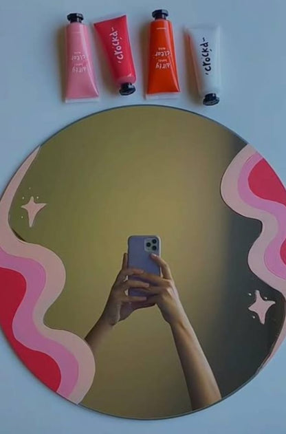 Hand holding a phone taking a mirror selfie with colorful lip products on a pink and red abstract design.