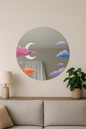 Round decorative mirror with cloud and moon design on a wall above a sofa.