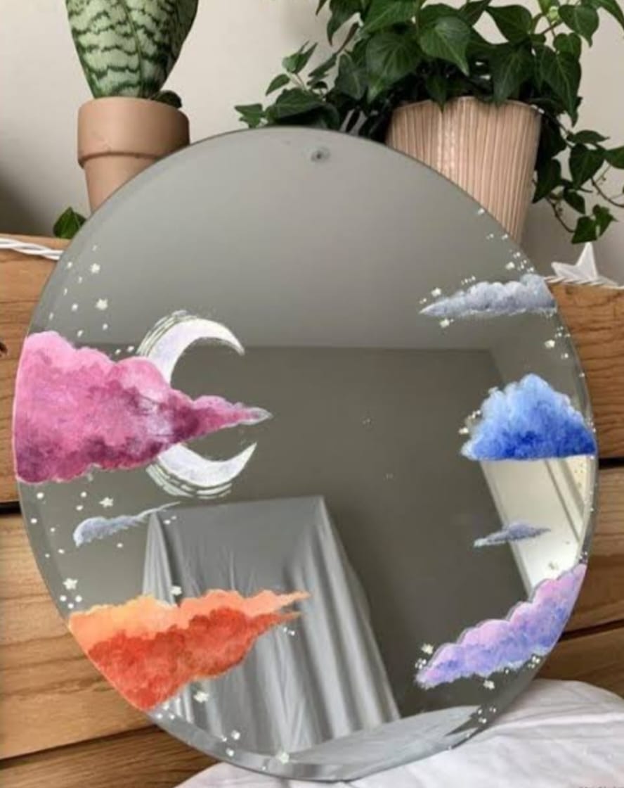 Round mirror with colorful cloud designs on a wooden surface