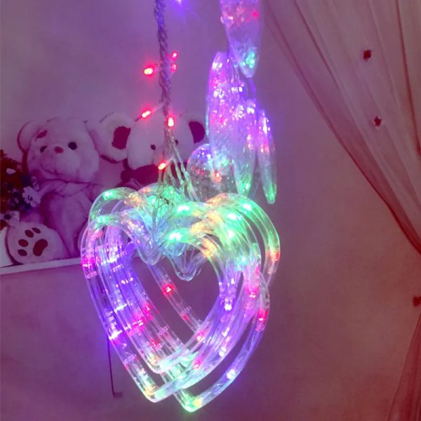 Heart-shaped LED light decoration with colorful lights on a plain background