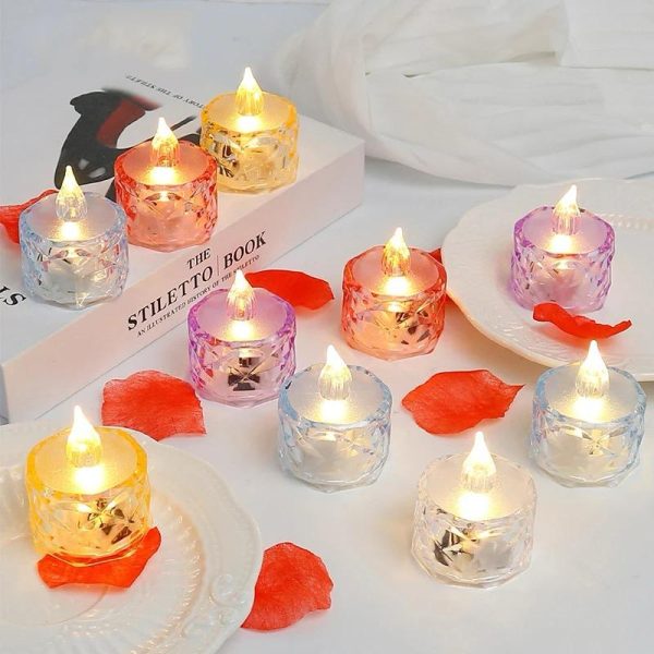 Colorful LED candles on a white surface with red flower petals