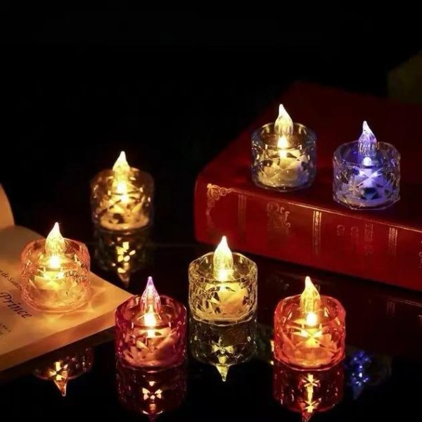 Set of colorful LED candles in glass holders on a reflective surface.