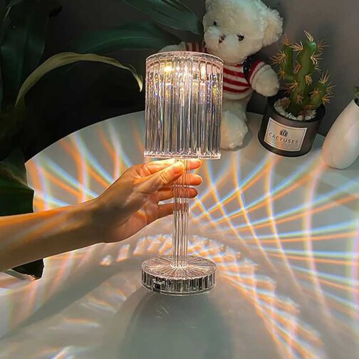 Crystal lamp being held with a decorative background including a teddy bear and plants.