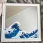 Framed artwork of a blue wave on a neutral background